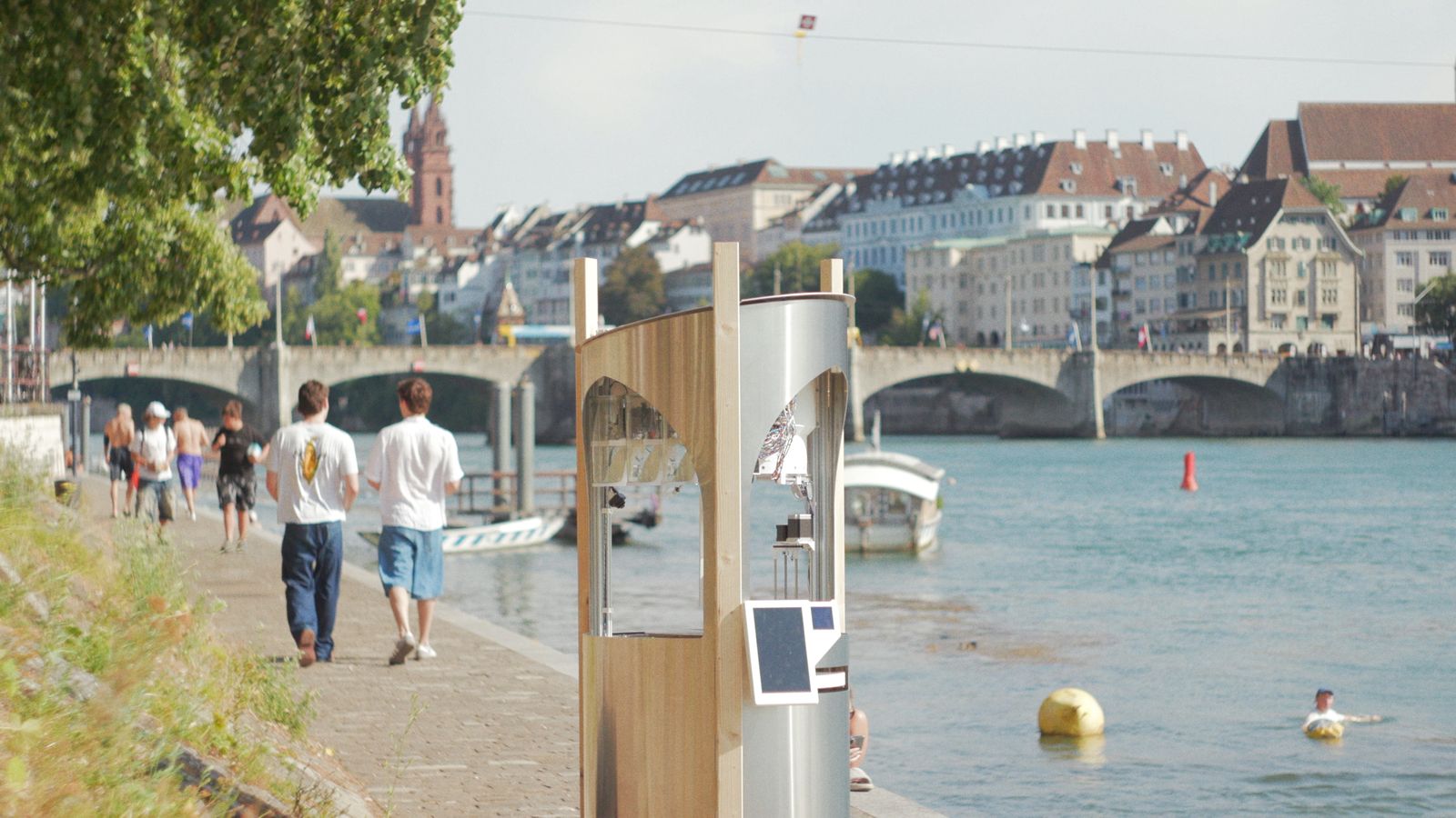 Passantinnen und Passanten gehen an der Rheinpromenade in Basel am Roboter vorbei.
